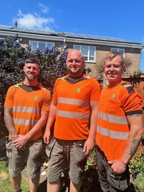 Three Oil Tank Replacement Services engineers in orange hi-vis workwear standing together outside a customer's house
